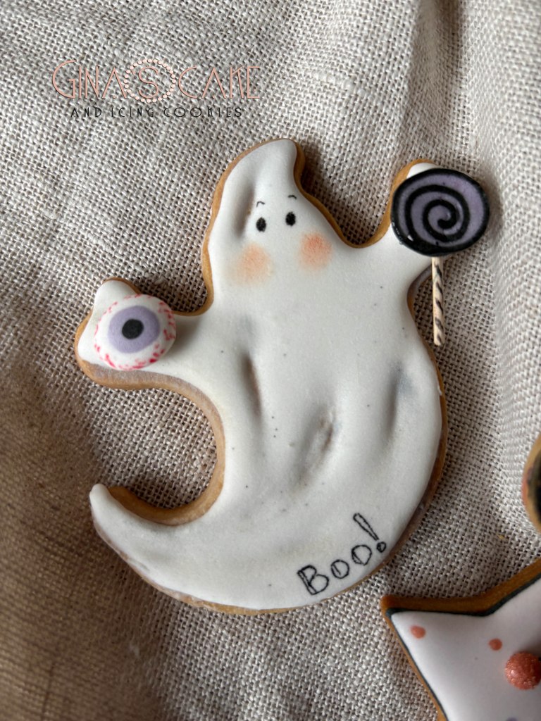 Biscotto decorato a forma di fantasma con un occhio e un lecca-lecca, con la scritta 'Boo!'