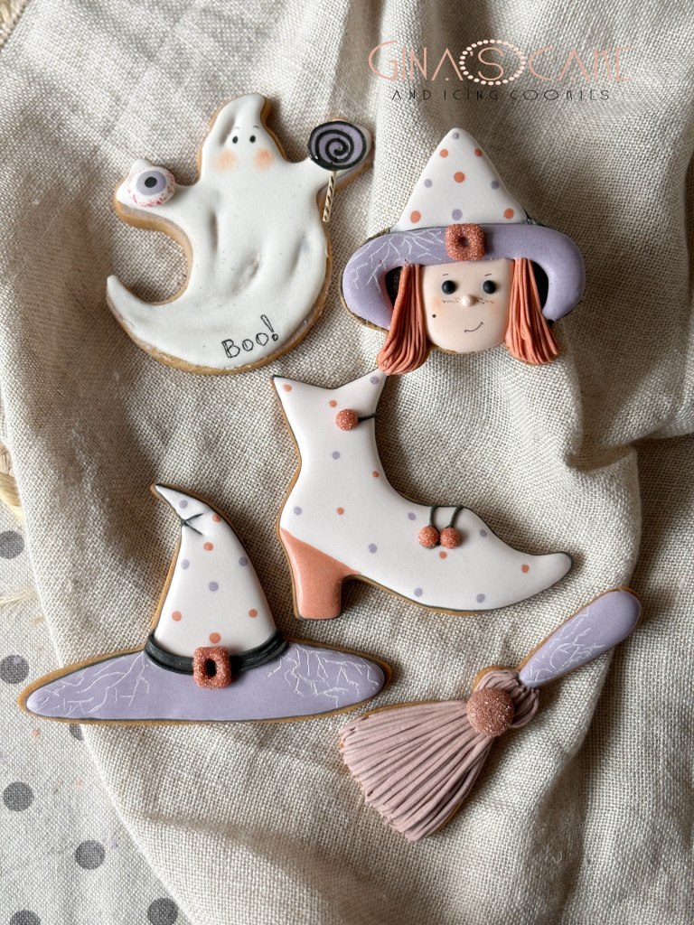 Biscotti decorati a tema Halloween, tra cui un fantasma, un cappello da strega, una scopa e una scarpa di strega.