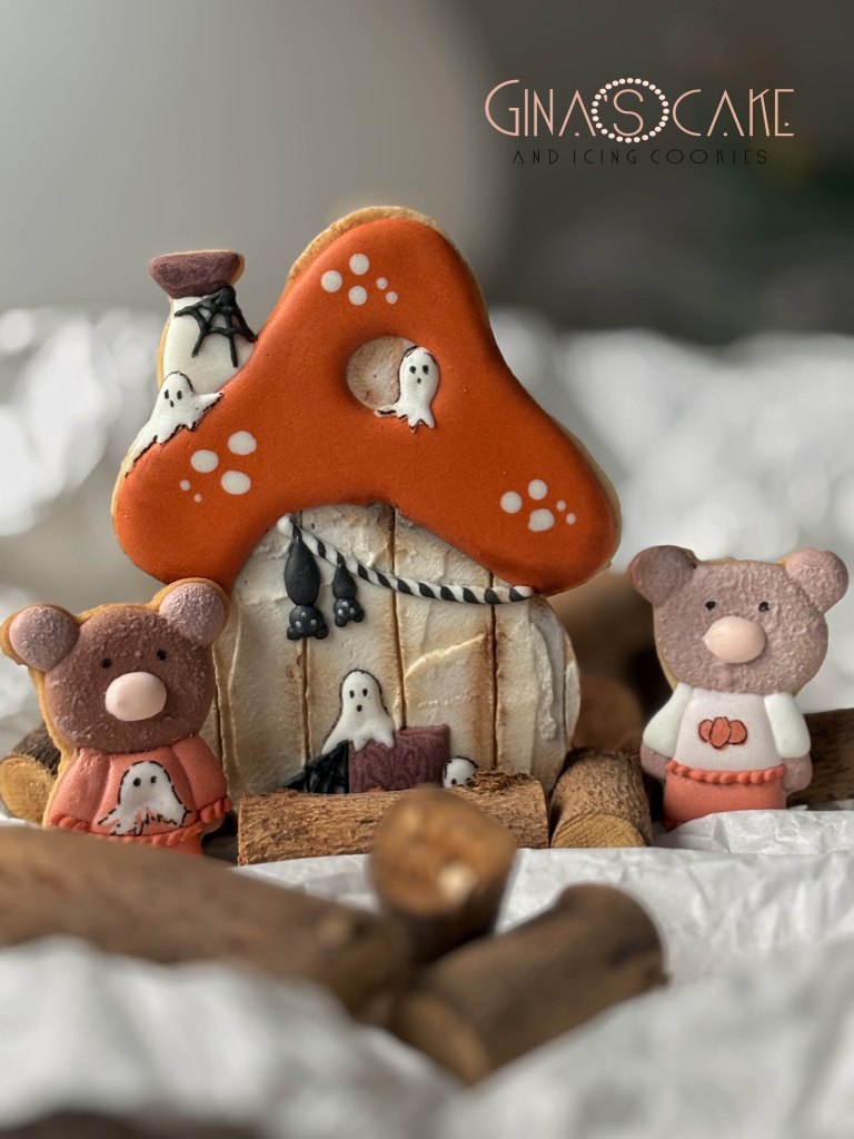 Biscotti decorati a forma di casa stregata con fantasmini, accompagnati da orsetti di pasta di zucchero.